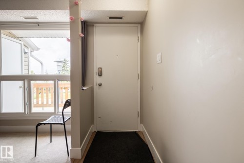 Entryway featuring a light-colored door with modern hardware, leading to a space with a multi-pane window - 8 2703 79 Street, Edmonton, AB 