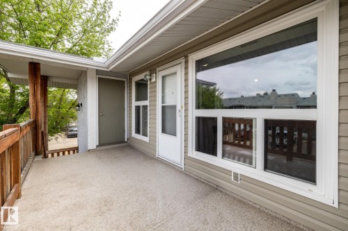 Exterior balcony featuring a textured concrete surface, wood railing, and exposed wood support beams - 8 2703 79 Street, Edmonton, AB 