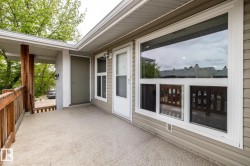 Exterior balcony featuring a textured concrete surface, wood railing, and exposed wood support beams - 