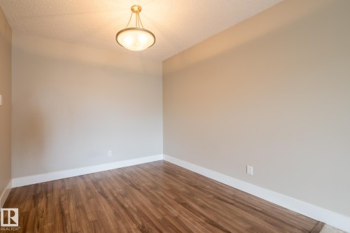 Room featuring wood-finish flooring, neutral wall paint, white baseboards, and a ceiling-mounted light fixture - 8 2703 79 Street, Edmonton, AB 