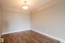 Room featuring wood-finish flooring, neutral wall paint, white baseboards, and a ceiling-mounted light fixture - 