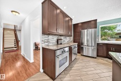 Modern kitchen featuring rich wood-finish cabinetry, stainless steel appliances, and light-toned countertops - 