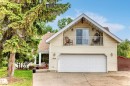 Exterior featuring light-colored siding, a prominent two-car garage with a panel door, and an upper-level balcony with white railings - 8224 186 Street Nw, Edmonton, AB 