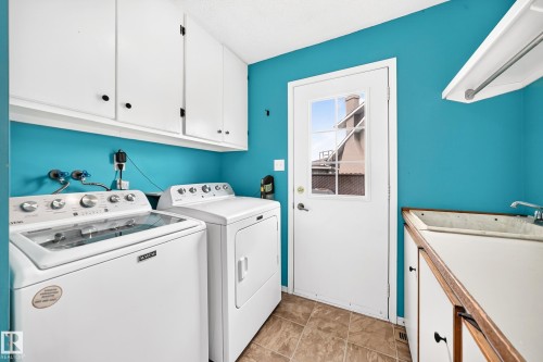 Utility room featuring white cabinetry, a built-in sink with countertop, and durable tile flooring - 8224 186 Street Nw, Edmonton, AB 
