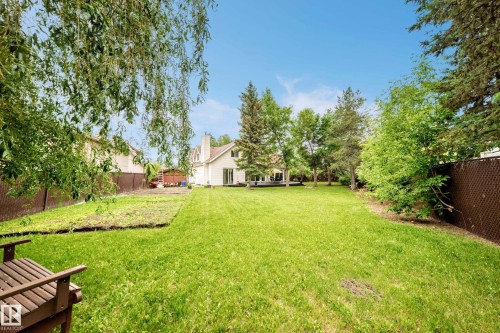 Expansive green lawn with mature trees and perimeter fencing - 8224 186 Street Nw, Edmonton, AB 
