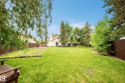 Expansive green lawn with mature trees and perimeter fencing - 