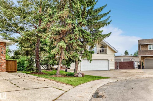 Cream-colored siding home featuring a white garage door and an upper-level balcony - 8224 186 Street Nw, Edmonton, AB 
