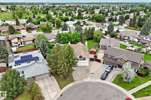 Aerial neighborhood panorama featuring multiple homes with pitched roofs, mature trees, and concrete driveways - 8224 186 Street Nw, Edmonton, AB 