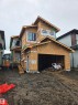Multi-level new construction featuring a prominent front entrance, multiple contemporary windows, an attached garage, and a developing exterior - 113 29A Street, Edmonton, AB 