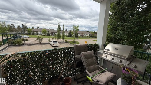 Covered balcony offering outdoor living space, featuring a privacy screen and a metal railing - 202 13635 34 Street, Edmonton, AB 