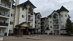 Multi-story condominium building featuring light-toned siding and dark pitched roofs - 