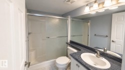 Bathroom featuring a vanity with an oval sink, a blue speckled countertop, and a large mirror with a four-light fixture - 
