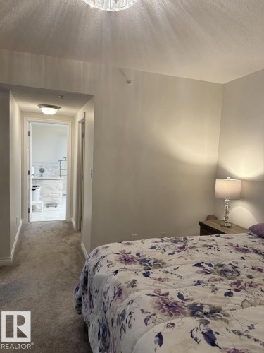 Plush carpeting throughout, leading to a bathroom featuring white tile flooring and a built-in tub with a tile surround - 305 11111 82 Avenue, Edmonton, AB 