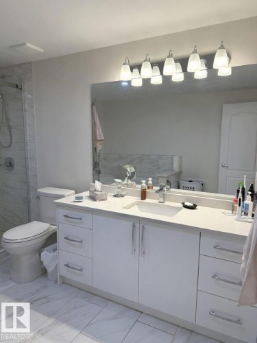 Contemporary bathroom featuring a spacious white vanity with ample storage, a large integrated sink, and a sleek countertop - 305 11111 82 Avenue, Edmonton, AB 