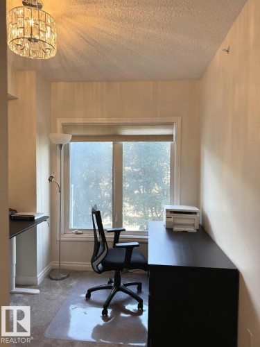 Bright room featuring a large window, neutral wall tones, textured ceiling, and recessed shelving - 305 11111 82 Avenue, Edmonton, AB 