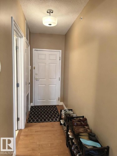 Entryway featuring a paneled door with brushed nickel hardware, wood-finish flooring, and a flush-mount ceiling light - 305 11111 82 Avenue, Edmonton, AB 