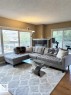 Living area featuring wood-finish flooring, a corner fireplace with a dark-toned surround and white mantel, and large windows with white trim - 305 11111 82 Avenue, Edmonton, AB 