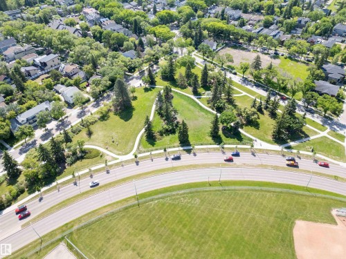 Aerial perspective showcasing a residential neighborhood with mature trees, green spaces, and paved pathways - 305 11111 82 Avenue, Edmonton, AB 