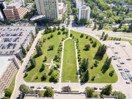 Expansive green space featuring a central pathway, mature trees, and surrounding urban infrastructure - 305 11111 82 Avenue, Edmonton, AB 
