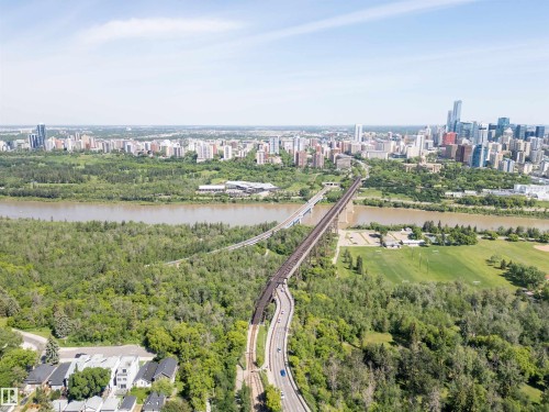Expansive river valley landscape featuring a winding river, dense green forests, multiple bridge structures, and a distant cityscape with numerous high-rise buildings - 305 11111 82 Avenue, Edmonton, AB 