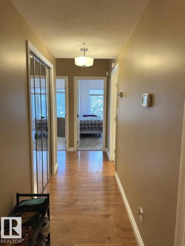 Hallway featuring wood-finish flooring, a semi-flush mount ceiling light fixture, and neutral wall tones - 305 11111 82 Avenue, Edmonton, AB 