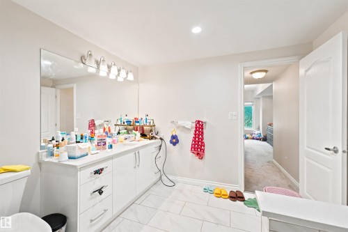 Bathroom featuring a double vanity with white cabinetry, a large wall-mounted mirror, and a six-light fixture - 305 11111 82 Avenue, Edmonton, AB 