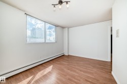 Open room featuring wood-finish flooring, white walls, and a large window with a building backdrop - 