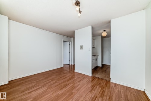 Spacious room featuring wood-finish flooring, white baseboards, and a neutral color palette - 401 11007 83 Avenue, Edmonton, AB 