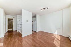 Open-concept living space featuring wood-finish flooring, built-in shelving, track lighting, and white walls - 