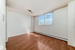 Spacious room featuring wood-finish flooring, a large window, and track lighting - 