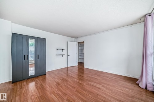 Spacious room featuring wood-finish flooring, white walls, and a window with curtain rod - 401 11007 83 Avenue, Edmonton, AB 