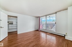 Living area featuring wood-finish flooring, white walls, and a full-height sliding glass door - 