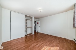 Bedroom featuring wood-finish flooring, white walls, and a built-in closet with sliding doors and integrated shelving - 