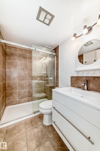 Contemporary bathroom featuring a white vanity with integrated sink, chrome faucet, and pull-out drawers - 401 11007 83 Avenue, Edmonton, AB 