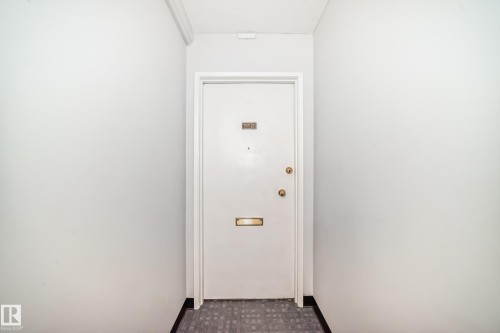Entryway featuring a white door with brass hardware, a brass mail slot, and a peephole - 401 11007 83 Avenue, Edmonton, AB 
