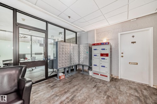 Common area featuring wood-finish flooring, glass-paneled office entry, and multiple mailboxes - 401 11007 83 Avenue, Edmonton, AB 