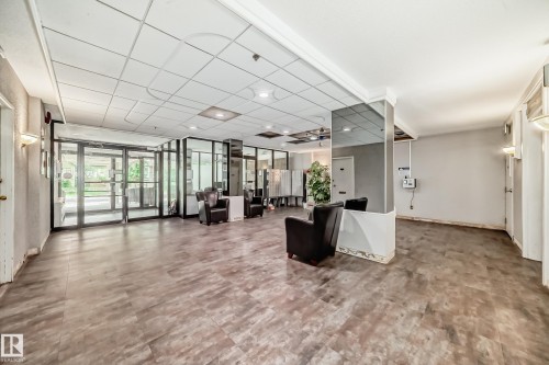 Lobby area featuring wood-finish flooring, glass entry doors, and overhead ceiling tiles - 401 11007 83 Avenue, Edmonton, AB 