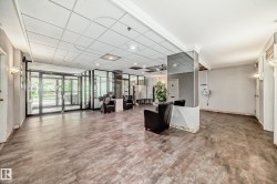 Lobby area featuring wood-finish flooring, glass entry doors, and overhead ceiling tiles - 