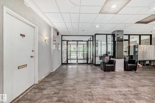 Spacious common area featuring wood-finish flooring, glass-paneled walls, and built-in lighting - 401 11007 83 Avenue, Edmonton, AB 