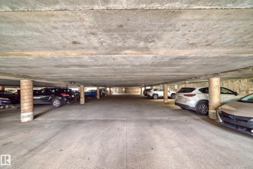 Covered parking structure featuring concrete flooring and ceiling, supported by cylindrical columns - 401 11007 83 Avenue, Edmonton, AB 