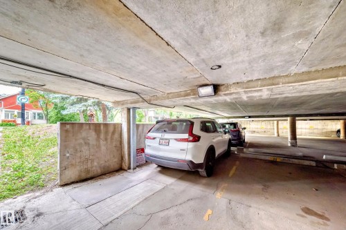 Covered parking area featuring concrete flooring, concrete support columns, and an integrated lighting fixture - 401 11007 83 Avenue, Edmonton, AB 