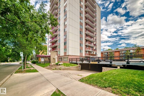 High-rise building with extensive balconies featuring red railings, a street-level entrance with a canopy, and an underground parking entrance - 401 11007 83 Avenue, Edmonton, AB 