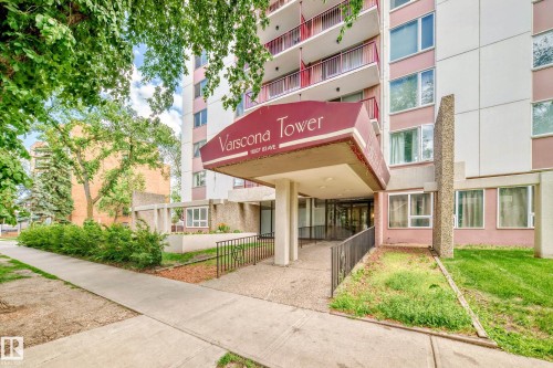 Multi-story building entrance featuring a covered awning with "Varscona Tower" signage, a paved walkway, a ramp with a handrail, and surrounding greenery - 401 11007 83 Avenue, Edmonton, AB 