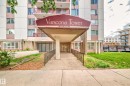 Building entrance featuring a covered portico with signage, a concrete walkway, and black metal railings - 401 11007 83 Avenue, Edmonton, AB 