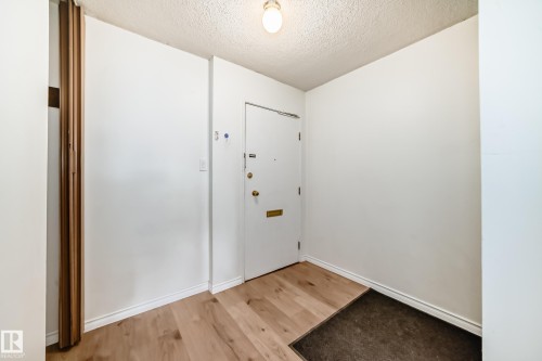 Entryway featuring wood-finish flooring, white walls, and a recessed ceiling light fixture - 401 11007 83 Avenue, Edmonton, AB 