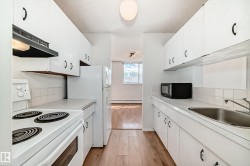 Galley kitchen featuring white cabinetry, a built-in range hood, and a white tile backsplash - 