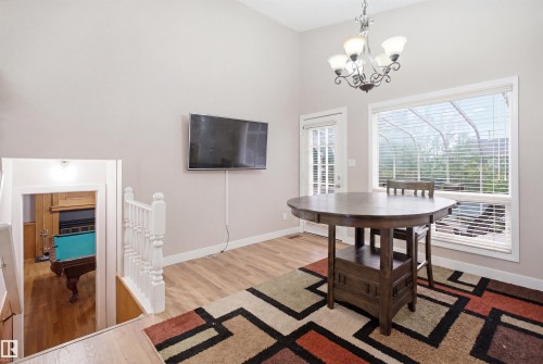 Vaulted ceiling with an ornate chandelier, a large window with blinds, and a door with lites - 3220 42A Avenue, Edmonton, AB 