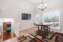 Vaulted ceiling with an ornate chandelier, a large window with blinds, and a door with lites - 