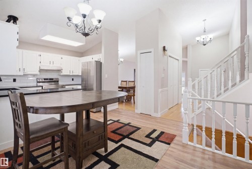 Open-concept kitchen with white cabinetry, stainless steel appliances, and a dark countertop - 3220 42A Avenue, Edmonton, AB 