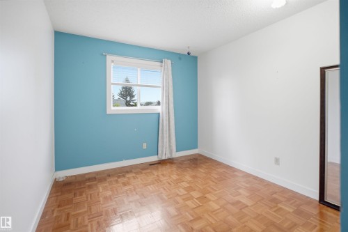 Room featuring wood-finish parquet flooring and white baseboards - 3220 42A Avenue, Edmonton, AB 